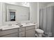 Bright bathroom featuring double sinks, white cabinets, a large mirror, and a shower with gray curtain at 124 Benford Dr, Troutman, NC 28166