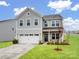 Charming two-story home with gray siding, a two car garage and a well-manicured lawn at 124 Benford Dr, Troutman, NC 28166