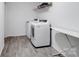 Well-lit laundry room with modern washer and dryer, gray wood-look flooring, and metal shelving at 124 Benford Dr, Troutman, NC 28166
