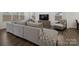 Comfortable living room with hardwood floors, a large gray sofa, and a modern TV stand at 124 Benford Dr, Troutman, NC 28166