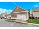 View of a two-car garage with white doors and brown siding, providing parking and storage at 12424 Bradford Park Dr, Davidson, NC 28036
