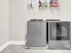 An organized laundry room features modern, gray front-loading washer and dryer sets plus a shelf for supplies at 12424 Bradford Park Dr, Davidson, NC 28036