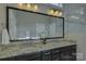 Bathroom vanity featuring a double sink, granite countertop, and decorative mirror at 14916 Creeks Edge Dr, Charlotte, NC 28278