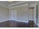 Neutral bedroom featuring dark hardwood floors, tray ceilings, and an ensuite doorway at 14916 Creeks Edge Dr, Charlotte, NC 28278