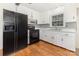 Traditional kitchen featuring white cabinetry, black appliances, wood floors and a window over the sink at 1519 Briarfield Dr, Charlotte, NC 28205