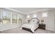 Sun-filled bedroom with large windows, tray ceiling, and neutral decor with lamps on the bedside tables at 15212 Keyes Meadow Way, Huntersville, NC 28078