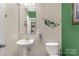 A half bathroom features a white sink, toilet, tan paint, and green accent wall at 1853 Beach Ln, Heath Springs, SC 29058