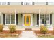 Inviting front porch with a vibrant yellow door, rocking chairs, and manicured landscaping at 1853 Beach Ln, Heath Springs, SC 29058