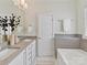 Well lit bathroom with double vanity, modern fixtures, and bathtub with gray tiled backsplash at 1904 Lela Ave, Charlotte, NC 28208