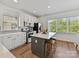 Bright kitchen features a center island with seating, white cabinets, stainless appliances, and wood floors at 1904 Lela Ave, Charlotte, NC 28208