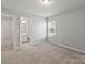 This bedroom features neutral walls, carpet and a window offering natural light plus an ensuite bathroom at 2031 Killian Creek Dr, Denver, NC 28037