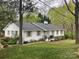 A single-story white brick home with a black roof and manicured front lawn at 2701 Rea Rd, Charlotte, NC 28226