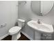 Powder room with a pedestal sink, round mirror, tiled floors, and modern fixtures that create a clean and sophisticated look at 3026 S Devon St, Charlotte, NC 28213
