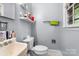 Bathroom with sink, toilet, shelf, and a window providing natural light at 3612 Winterfield Pl, Charlotte, NC 28205