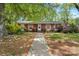 Daytime view of a charming single-story brick home with inviting walkway, surrounded by lush landscaping and mature trees at 3612 Winterfield Pl, Charlotte, NC 28205
