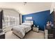 Bedroom featuring a blue accent wall, neutral carpet and a stylish bed with patterned bedding at 4528 Craigmoss Ln, Charlotte, NC 28278