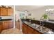 Open kitchen featuring granite counters, stainless sink and wood cabinetry with view to living room at 4528 Craigmoss Ln, Charlotte, NC 28278