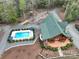 Stunning aerial view of a log cabin with a pool, lush landscaping, large deck and stone chimney at 528 Manchester Rd, Mount Gilead, NC 27306