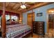 Cozy bedroom with log walls, ceiling fan, and four-poster bed with rustic-themed bedding at 528 Manchester Rd, Mount Gilead, NC 27306