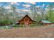 Stunning log cabin featuring a red front door, a stone wall, and a separate garage at 528 Manchester Rd, Mount Gilead, NC 27306