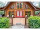 Charming log cabin with a welcoming front porch, bright red door, and beautiful natural wood accents at 528 Manchester Rd, Mount Gilead, NC 27306