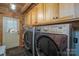 Modern laundry room with wooden cabinets, side-by-side washer and dryer, and slate tile flooring at 528 Manchester Rd, Mount Gilead, NC 27306