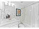 Bright bathroom with a white single sink vanity, poster art, and shower/tub combo with white tiling at 5924 Carrollton Ln, Charlotte, NC 28210