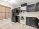 This kitchen features black cabinets, white appliances, and a window with a brown bamboo blind for natural light at 753 Mountainwater Dr, Charlotte, NC 28262