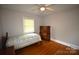 Bedroom with wooden floors, a ceiling fan, and a window with blinds, providing a cozy and comfortable space at 8608 Cedarbrook Dr, Charlotte, NC 28215