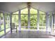 A sunroom with wood floors and lots of windows that look out on a green outdoor space at 8608 Cedarbrook Dr, Charlotte, NC 28215