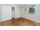 Bedroom featuring hardwood floors, a window, and ample closet space at 900 E Woodlawn Rd, Charlotte, NC 28209
