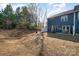 Large dormant backyard behind a blue house with a white fence and partial view of the home and surroundings at 9031 Odell Corners Nw Blvd, Concord, NC 28027