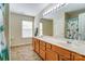 Bathroom featuring double sinks, light-toned wood cabinets, neutral walls, and a shower at 10421 Dominion Village Dr, Charlotte, NC 28269
