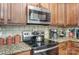 Updated kitchen with stainless steel appliances and granite countertops with wood cabinets and tile backsplash at 10421 Dominion Village Dr, Charlotte, NC 28269