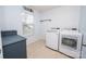 Bright laundry room featuring a modern washer and dryer, patterned wallpaper, and natural light from the window at 10694 Sapphire Trl, Davidson, NC 28036