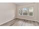 A bright bedroom with neutral walls, stylish flooring, and a large window overlooking the front yard at 12706 Ballyliffin Dr, Pineville, NC 28134
