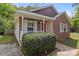 All brick home with a red door, complemented by white trim, manicured bushes, and a well-kept lawn at 2325 Sanders Ave, Charlotte, NC 28216