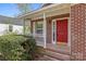 Red brick home with a bright red front door, accented by white trim and a cozy front porch at 2325 Sanders Ave, Charlotte, NC 28216