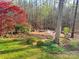 Serene backyard with brick patio, outdoor seating, mature trees, and lush landscaping at 245 Clontz Hill Rd, Troutman, NC 28166