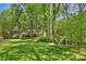 Backyard with firepit, chairs, and a view of the brick house and wooded area at 2605 Winding Oak Dr, Charlotte, NC 28270
