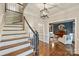 A foyer with hardwood floors, a staircase, and a view into a living room with a piano at 2605 Winding Oak Dr, Charlotte, NC 28270