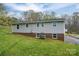 Exterior view of the home featuring gray siding, a brick foundation, and lush lawn at 3791 Richard St, Claremont, NC 28610