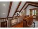 Hallway with exposed wood beams, stone accent wall and hardwood floors with railing at 418 3Rd Ne St, Hickory, NC 28601