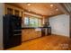 Bright kitchen featuring wood cabinets, black appliances, a farmhouse sink, hardwood floors, and a window with views at 418 3Rd Ne St, Hickory, NC 28601