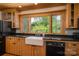 Well-lit kitchen with black countertops, light wood cabinets, a farmhouse sink, and a window overlooking the yard at 418 3Rd Ne St, Hickory, NC 28601