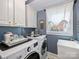 Efficient laundry room featuring modern appliances, white cabinets, and a window with a view at 6225 Woodleigh Oaks Dr, Charlotte, NC 28226