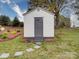 White storage shed with gray door and trim, surrounded by grass and landscaping at 630 Deese Rd, Monroe, NC 28110