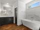 Bright bathroom featuring a standalone tub, marble walls, and a dark vanity with chrome finishes at 6700 Folger Dr, Charlotte, NC 28270