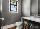 This bathroom features gray wallpaper, a small window, a toilet, and a black vanity with chrome finishes at 6700 Folger Dr, Charlotte, NC 28270
