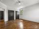 Empty bedroom with hardwood floors, white walls, a ceiling fan, and two black closets at 6700 Folger Dr, Charlotte, NC 28270